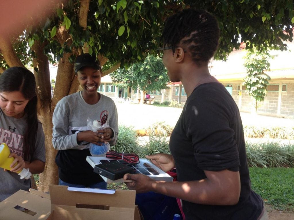 Two students talk under a tree