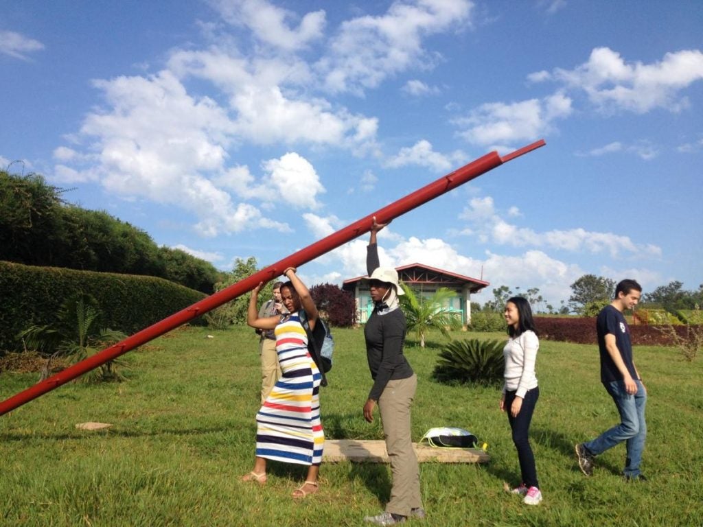 Multiple students hold up a pole that is being installed