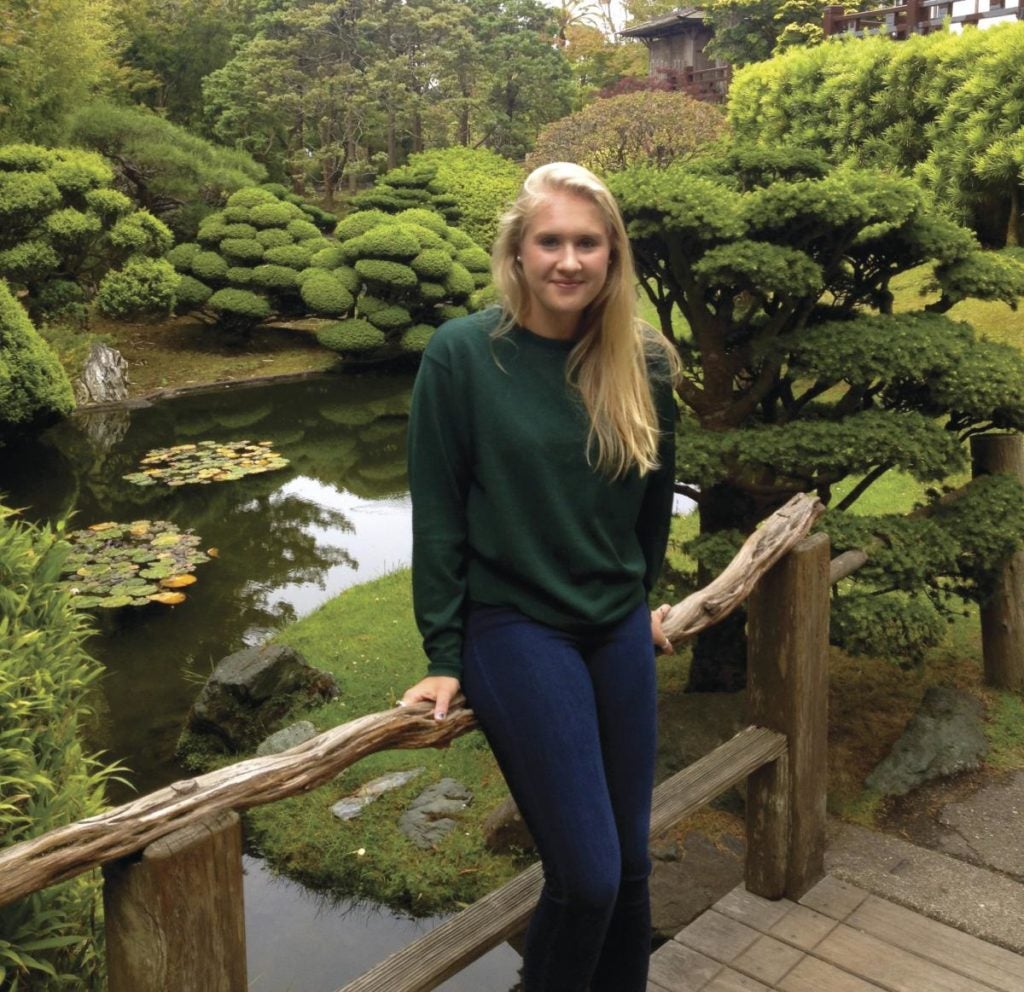 A girl poses in front of a pond