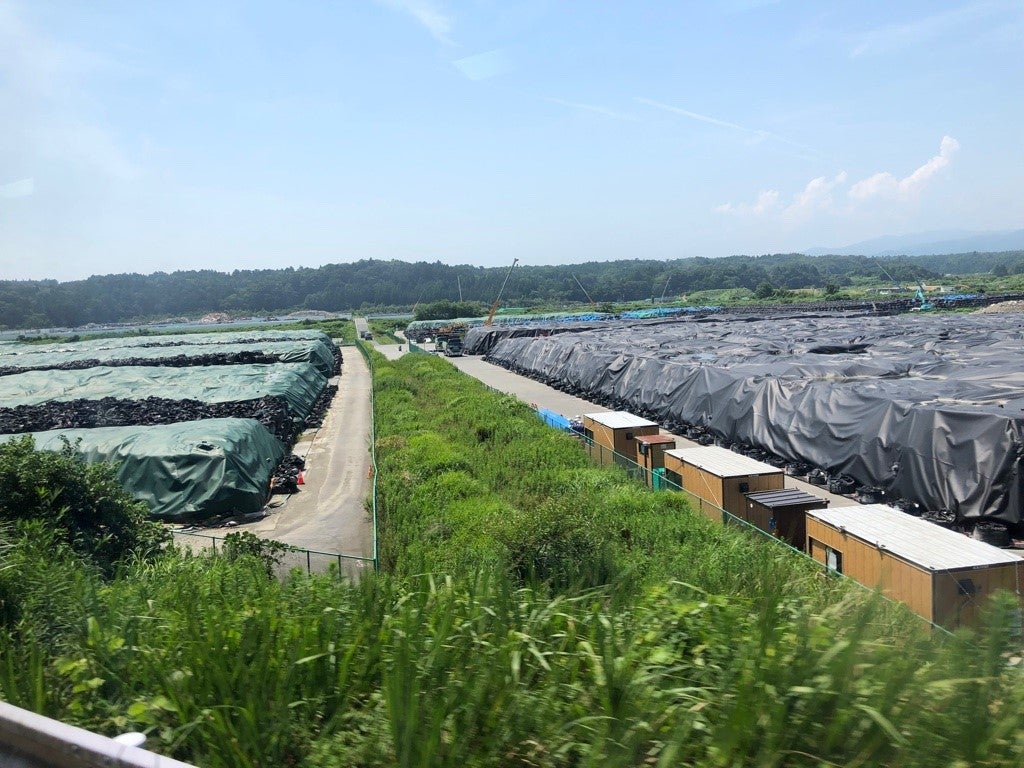 The green and black tarps cover mountains of contaminated topsoil bags. This temporary storage facility is just one of many inside the exclusion zone. 