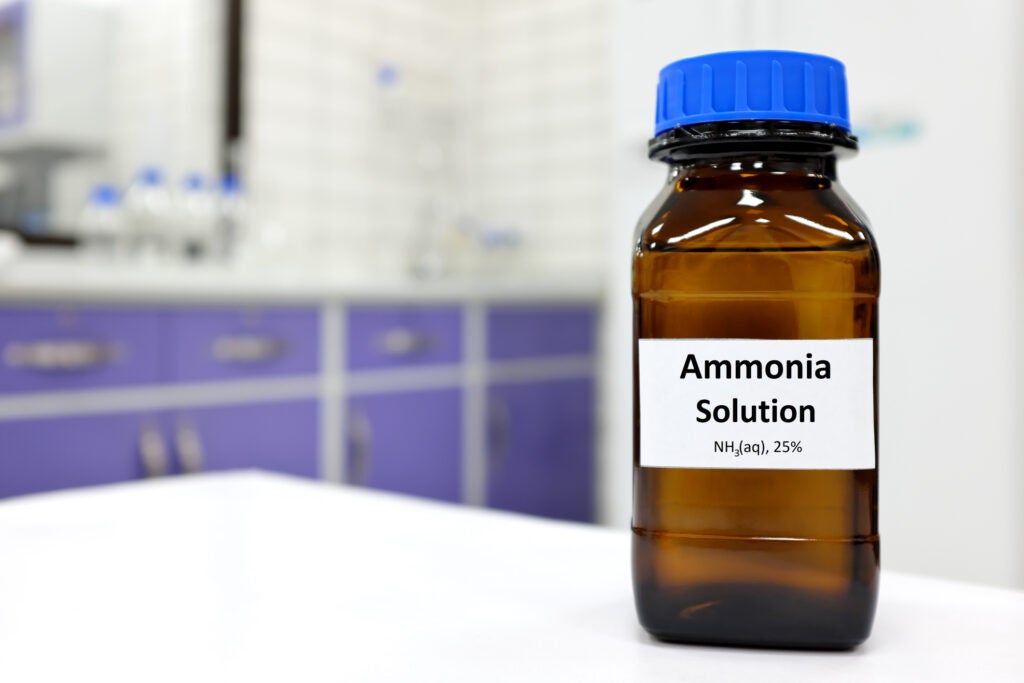 Selective focus of ammonia solution or ammonium hydroxide in glass amber bottle inside a chemistry laboratory with copy space.