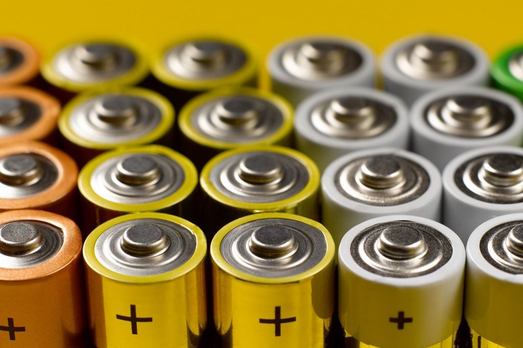 Closeup of a lot of color AA batteries on a bright yellow background.