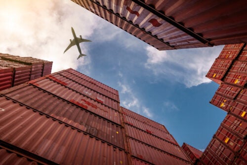 Airplane flying above container logistic. Cargo and shipping business. Container ship for import and export logistic. Logistic industry from port to port. Container at harbor for truck transport.