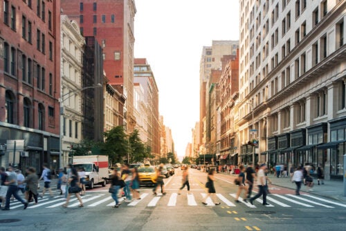 Crowds of people walking through a busy crosswalk at the intersection of 23rd Street and Fifth Avenue in Midtown Manhattan, New York City NYC